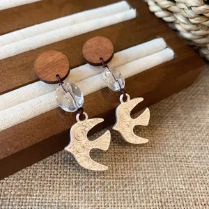 Close-up of vintage swallow bird pendant earrings with wood and crystal beads
