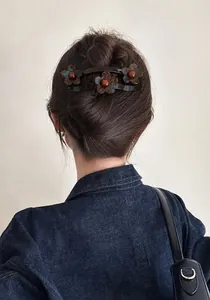 Detail van een grote acryl bloemen haarclip gestyled op een knotje van een vrouw