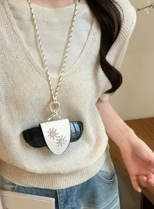 Detail of cream leather glasses holder necklace with sun embroidery on white knit vest.