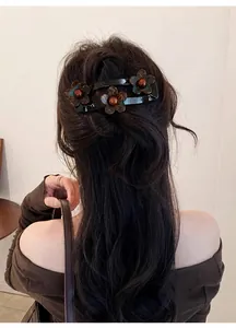 Detailopname van een elegante acryl schildpad bloem haarclip op lang zwart golvend haar