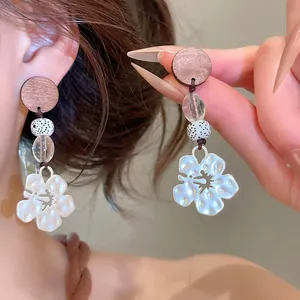 Detailed view of vintage flower dangle earrings with swallow cutout and wooden accent