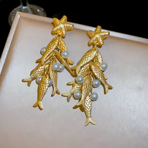 Detailed macro view of vintage gold fish and starfish earrings with white pearls.