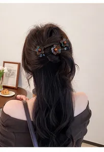 Detailweergave van een elegante acryl bloemen haarklem in lang golvend haar.