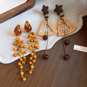 Primo piano di orecchini retrò in resina con perline di legno e triangolo intrecciato.