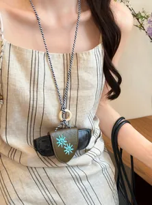 Close-up of olive leather eyewear holder necklace with blue sun embroidery on braided cord.