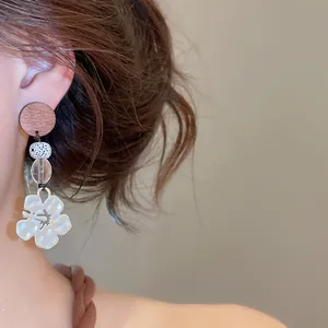 Close-up of vintage flower and swallow drop earring worn on ear, vacation style.