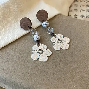 Close-up of vintage swallow and flower pendant earrings with wooden and bead accents