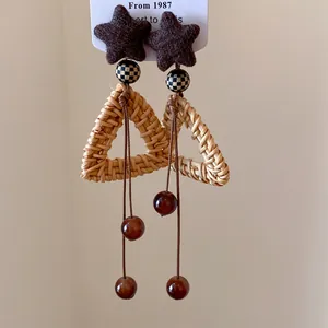 Dettaglio ravvicinato di orecchini in rattan vintage fatti a mano con stelle e perline