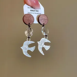 Macro view of vintage silver swallow earrings with wooden and glass beads