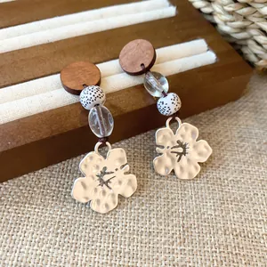 Detailed view of vintage wood and silver-toned flower drop earrings with swallow cutout