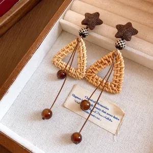 Dettaglio degli orecchini in rattan fatti a mano con nappe di perle in resina.