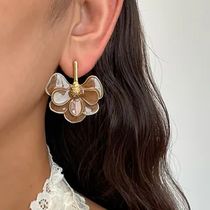 Close-up detail of vintage flower earrings with brown enamel petals on a model's ear
