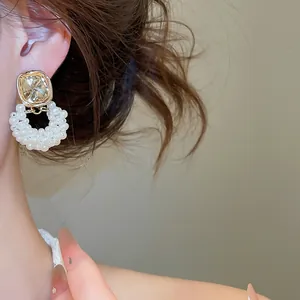 Nahaufnahme goldener französischer Vintage-Ohrringe mit weißem Perlenring am Modell