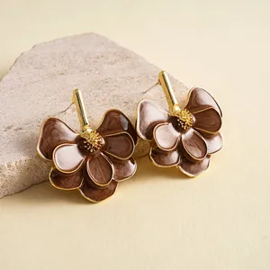 Detailed view of retro brown enamel flower stud earrings with elegant gold metal accents