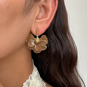 Detail shot of retro brown enamel flower earrings with gold-toned center on model