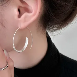 Detailed close-up showing a minimalist silver curved hoop earring worn on a model's ear