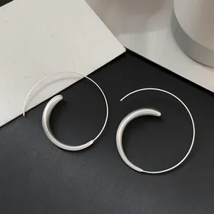 Detailed view of the unique silver spiral hoop earring with a minimalist matte finish