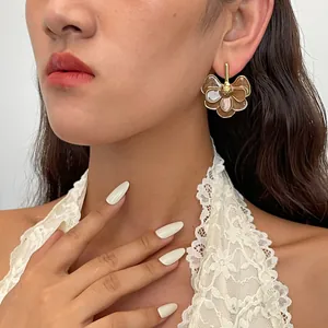 Close-up detail of vintage metal flower petal drop earrings worn by an Asian model.