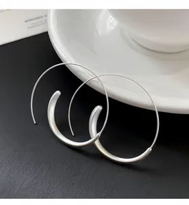 Detail of minimalist silver hoop earrings featuring a unique thick C-shape design