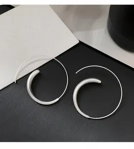 Macro view of minimalist silver spiral hoop earrings with elegant curved hook design