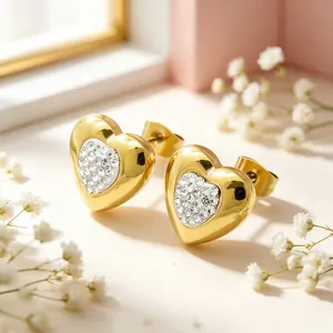 Gros plan de boucles d'oreilles cœurs dorés avec incrustation de strass sur fond doux.