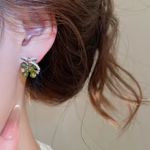 Detail van groene druif oorbellen met zirkoon strik gedragen aan het oor voor luxe