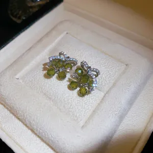 Elegante groene druifvormige oorknoppen met zirkoon strikdetail in een sieradendoos