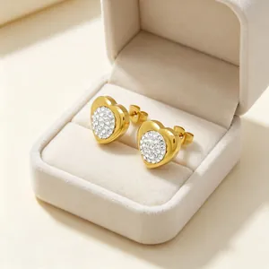 Gros plan de boucles d'oreilles cœur dorées avec strass pavés dans une boîte à bijoux en velours