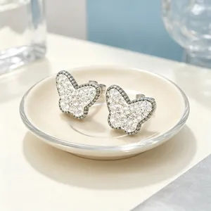 Gros plan de boucles d'oreilles papillon avec strass étincelants sur acier titane.
