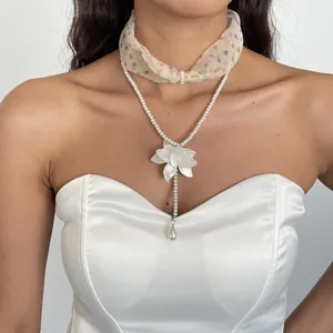 Detailed view of an elegant pearl and resin flower necklace with polka dot scarf