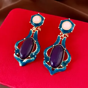 Elegante Vintage-Ohrringe mit blau-lilanem Harzanhänger auf rotem Samt-Display-Hintergrund