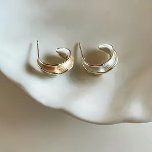 Vue détaillée de boucles d'oreilles clous plissées bicolores argent et or pour femme.