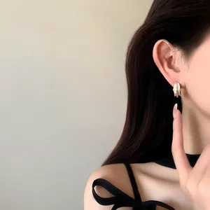 Gros plan de boucles d'oreilles plissées or et argent portées par un mannequin