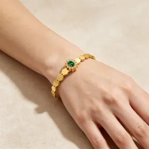Gros plan d'un bracelet hexagonal plaqué or 18 carats avec une gemme tournesol verte.
