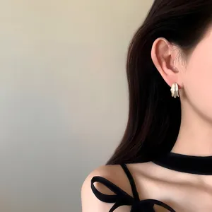Gros plan sur d'élégantes boucles d'oreilles créoles bicolores plissées sur un mannequin