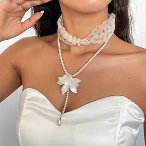 Close-up of elegant double-layer white pearl and chiffon floral necklace on a model wearing dress