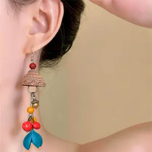 Close-up of ethnic style wooden drop earrings with colorful beads and blue petal