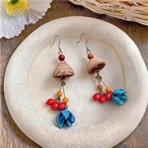 Detailed view of handmade ethnic wooden earrings with blue flowers and red beads