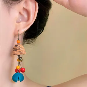 Detail shot of ethnic wood flower pendant earring with vibrant beads and teal flower.