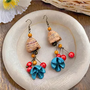 Detail of ethnic wooden earrings with colorful beads and teal fabric flower drops