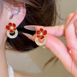 Gros plan de boucles d'oreilles fleur en émail rouge plaqué or 18 carats et pierres CZ