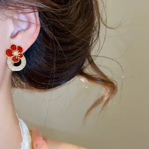 Gros plan d'une boucle d'oreille fleur en émail rouge plaquée or 18 carats avec zircon