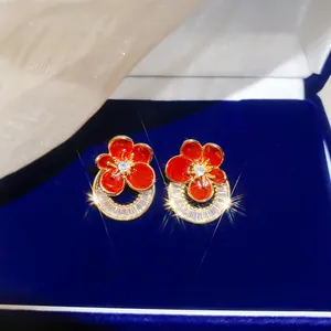 Détail des boucles d'oreilles fleur en émail rouge plaquées or 18K avec zircons brillants