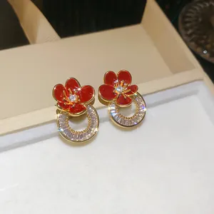 Vue détaillée des boucles d'oreilles fleur en émail rouge plaqué or 18 carats et oxydes.