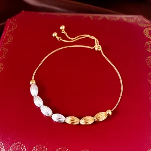 Detail eines 18k vergoldeten Armbands mit strukturierten ovalen Perlen auf Box