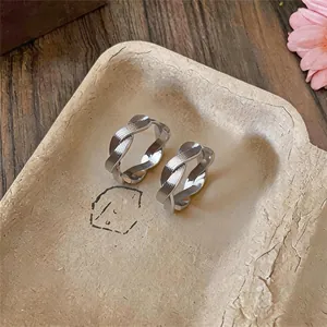 Nahaufnahme von verdrehten silbernen Metall-Ohrklemmen im minimalistischen Design