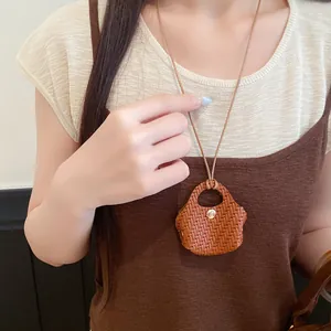 Woven leather mini bag pendant necklace shown worn as a stylish fashion accessory