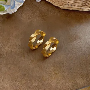Nahaufnahme goldener minimalistischer gedrehter Reifenohrringe mit eleganter Textur.