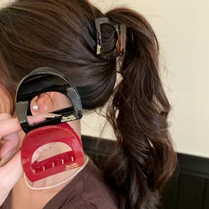 Détail de petites pinces à cheveux en acrylique en noir, rouge et écaille de tortue.