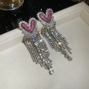 Glinsterende hartvormige hangende oorbellen met roze zirkonia en kristallen kwastjes.